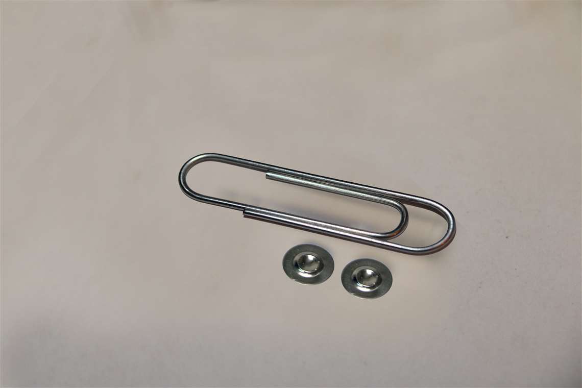 BS&B Safety System's custom engineered rupture disk is shown with a paper clip for scale.