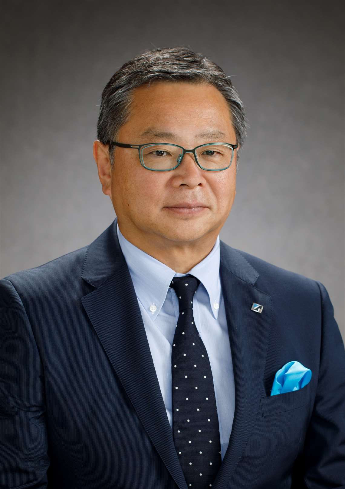Toshiaki Ujiie corporate portrait in dark suit and tie, Tadano blue hanky